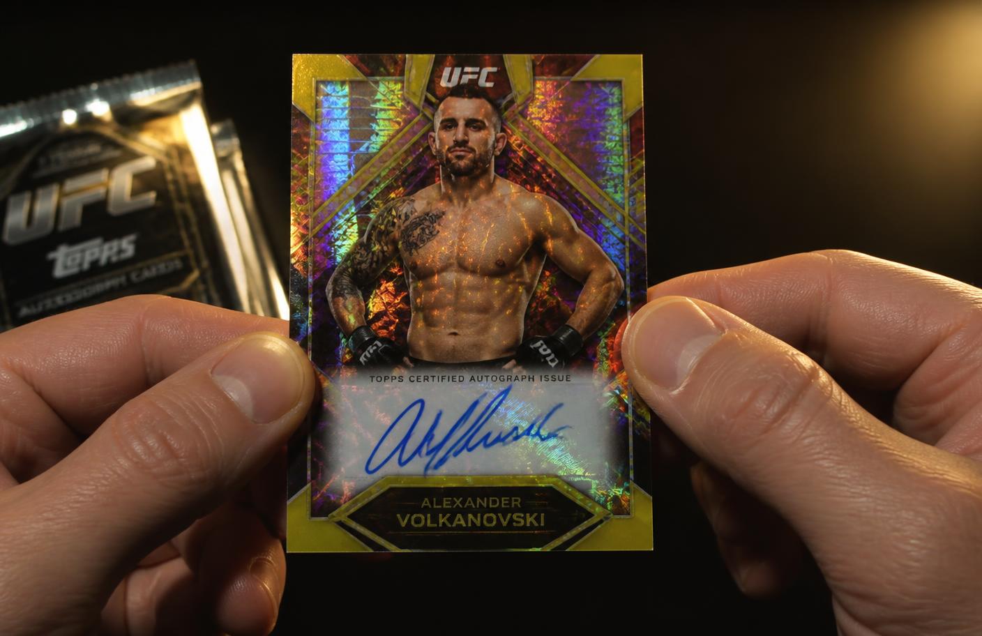 Hands holding a rainbow refractor autograph card fresh out of the pack